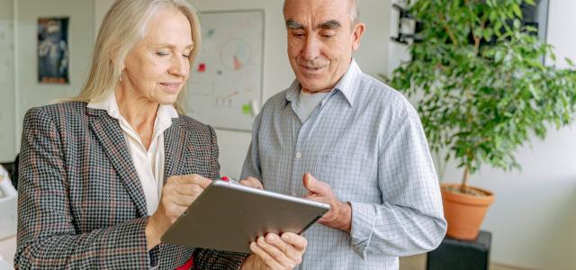 Two older businesspeople looking at a tablet screen