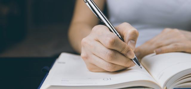 Woman writing in a paper planner with a pen